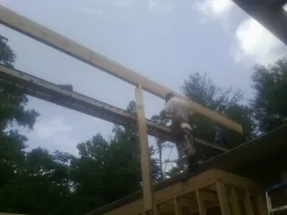 Carpenter setting a ridge beam over a new addition frame — Ice Dam Removal by Roofing Brothers in Johnson