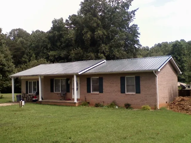Gray metal roof on a brick ranch house with a side carport in Johnson