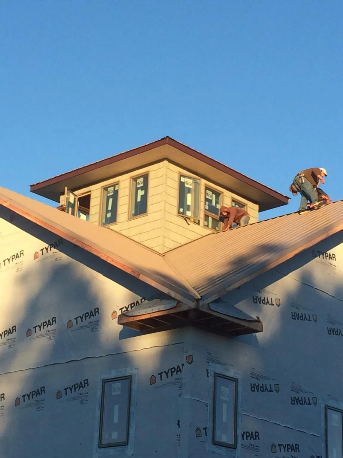 Roofers working around a rooftop cupola on a new metal roof at sunset — Roof Waterproofing in Johnson by Roofing Brothers